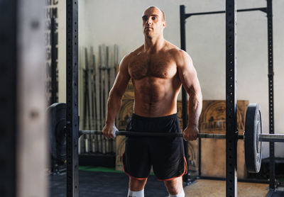 Shirtless man lifting barbell in gym