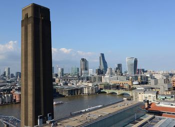 Modern buildings by river against sky in city
