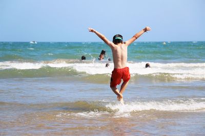 Full length of shirtless boy jumping on beach