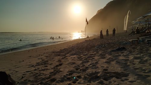 People on beach against sky during sunset