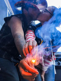 Midsection of man and woman holding sparkler 