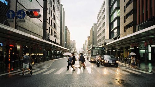 People on road by buildings in city