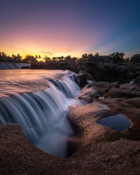 Scenic view of waterfall against sky during sunset