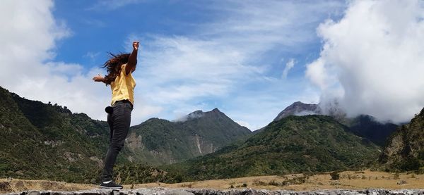 Woman with arms raised against sky