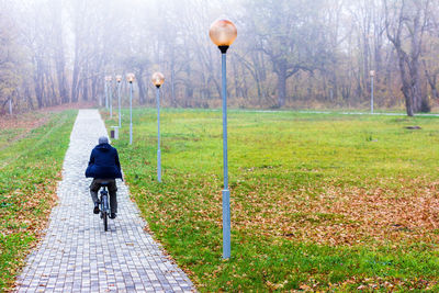 Rear view of man riding bicycle on field