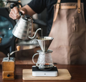 Man pouring coffee in cup on table