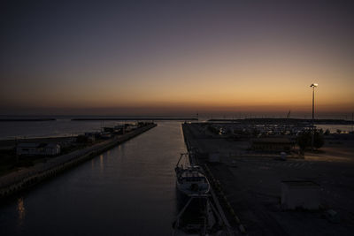 Boats moored at harbor against sky during sunset