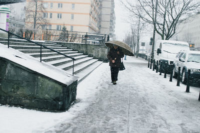 Person walking on snow covered city during winter