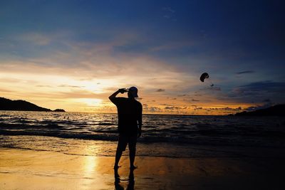 Man photographing sea against sky during sunset