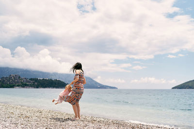 Woman standing on beach by sea against sky