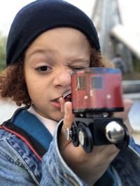 Close-up portrait of boy holding camera