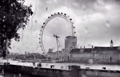 Low angle view of ferris wheel against cloudy sky