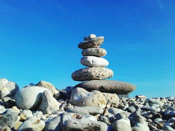 Stack of pebbles on beach against clear blue sky
