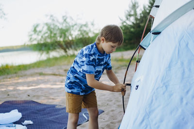 Cute little caucasian boy helping to put up a tent. family camping concept