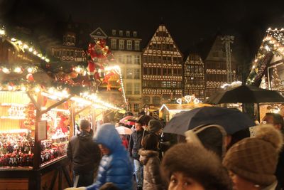 People on illuminated christmas tree in city during winter