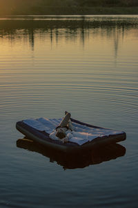 Young woman lies on a mattress on the water during sunset