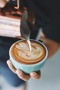 Close-up of person preparing cappuccino