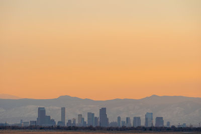 Buildings in city against orange sky