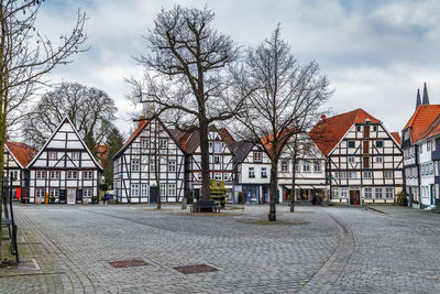 Houses by street and buildings against sky