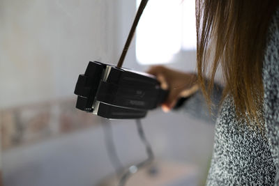 Woman ironing her hair with a hair iron.