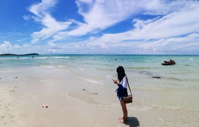 Woman standing on beach against sky