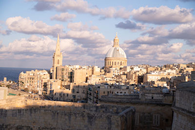 Buildings in city against cloudy sky