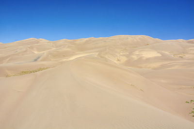 Scenic view of desert against clear blue sky