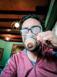 Portrait of young man holding eyeglasses at home