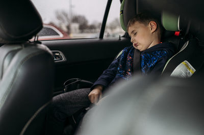 Boy sleeping in car seat in car on cloud day in kyle texas