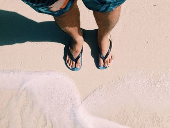 Low section of man standing on beach