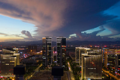 Illuminated buildings in city against sky at dusk