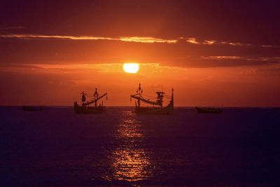 Silhouette boat in sea against sky during sunset