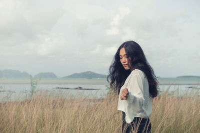 Asian long hair girl in white clothes enjoys life in nature coastal field.