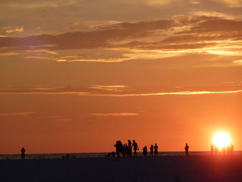 Silhouette people on beach at sunset