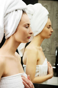 Reflection of woman wearing towel in mirror at bathroom