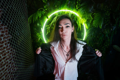 Portrait of young woman standing against wall