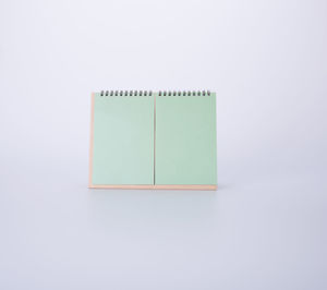 High angle view of blank green desk calendar against white background