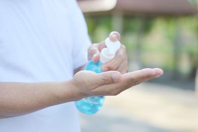 Close-up of hand holding bottle against blurred background