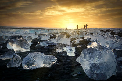 Rocks on shore against sky during sunset