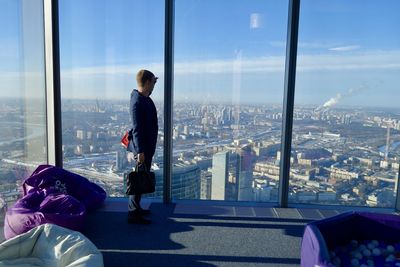 Woman looking at city buildings seen through glass window