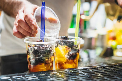 Bartender prepares a mixed fruit with soda water, fruit and syrup in a typical kiosk in catania.