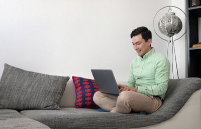 Man using laptop while sitting on sofa at home