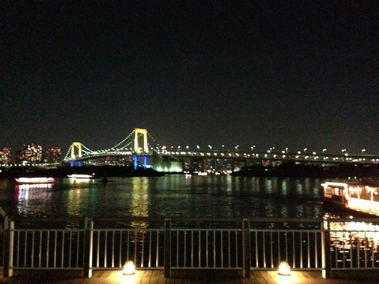 illuminated, night, architecture, built structure, bridge - man made structure, connection, water, river, bridge, reflection, city, lighting equipment, building exterior, copy space, clear sky, engineering, street light, sky, railing, outdoors