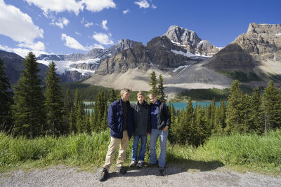 Portrait of family standing on mountain in forest against sky