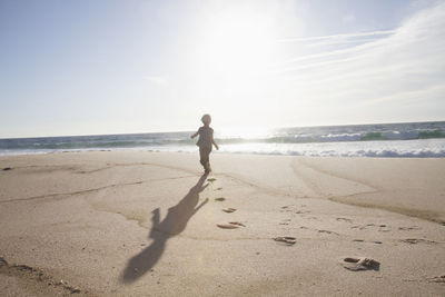 Back view of boy running on the beach at twilight