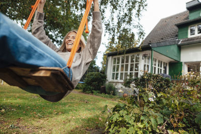 Happy woman swinging on swing at backyard