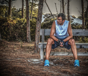 Full length of man sitting on swing in forest