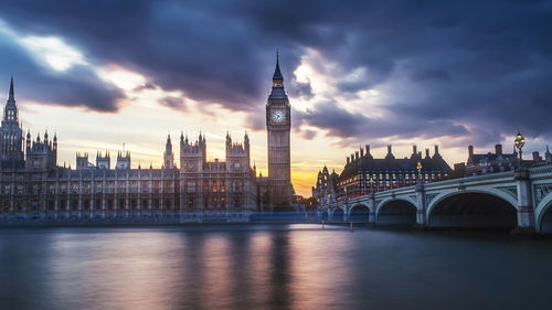 Big ben over river and buildings against sky in city