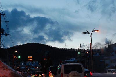 Traffic on road against cloudy sky