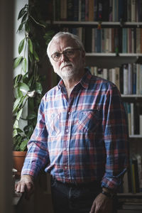 Portrait of senior therapist standing by potted plant at home office